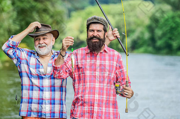 渔夫钓鱼杆有胡子的但捕捉鱼成熟的男人。朋友钓鱼夏天假期快乐快乐的人家庭时间活动爱好钓鱼淡水湖池塘河