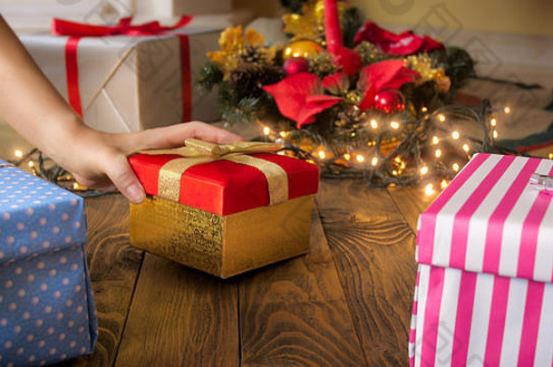 特写镜头图像女手把礼物盒子圣诞节树木地板上