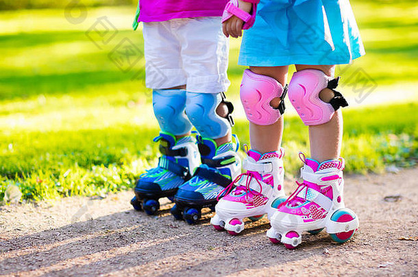 女孩男孩学习辊滑冰夏天公园孩子们穿保护垫安全头盔安全辊滑冰骑