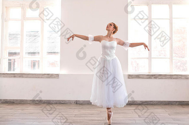 年轻的优雅的芭蕾舞女演员跳舞白色工作室