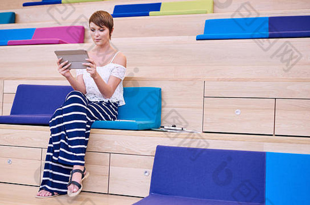 年轻的女人坐着色彩鲜艳的垫子工作空间