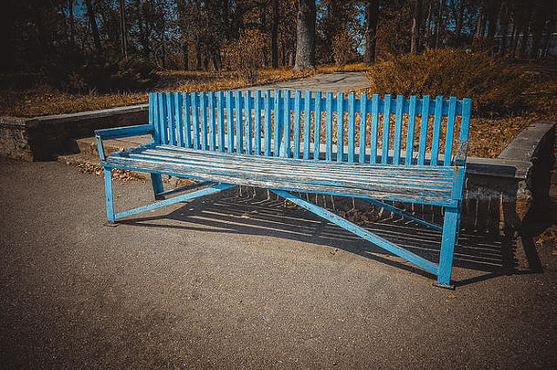 蓝色的木板凳上阳光明媚的秋天公园