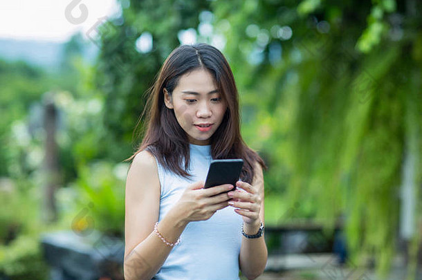 亚洲女孩放松花园手机检查文本