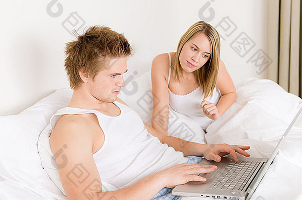 卧室年轻的夫妇移动PC书白色床上