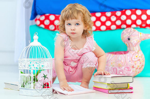 可爱的卷曲的女孩粉红色的睡衣看书坐着地板上孩子们的卧室相机