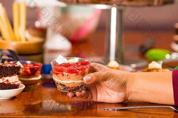 手抓住美味的摩丝覆盖草莓一流的提出了内部小玻璃蛋糕块松饼背景糕点概念