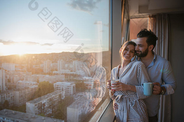 浪漫的快乐年轻的夫妇享受晚上咖啡美丽的日落景观城市站窗口