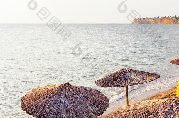 视图早期早....太阳黎明公共海滩茅草遮阳篷雨伞躺椅海海岸线