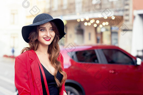 美丽的高加索人微笑年轻的女人穿黑色的他红色的车背景城市街