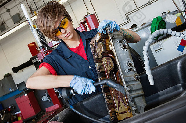 年轻的女机械师工作焊接火炬车辆机械部分汽车修复商店