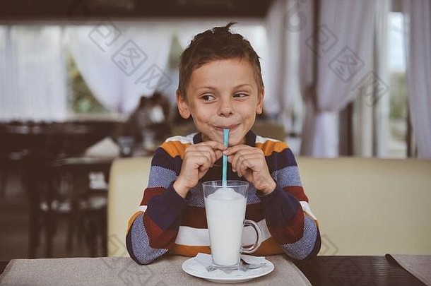 快乐微笑男孩色彩斑斓的毛衣喝牛奶摇饮料稻草