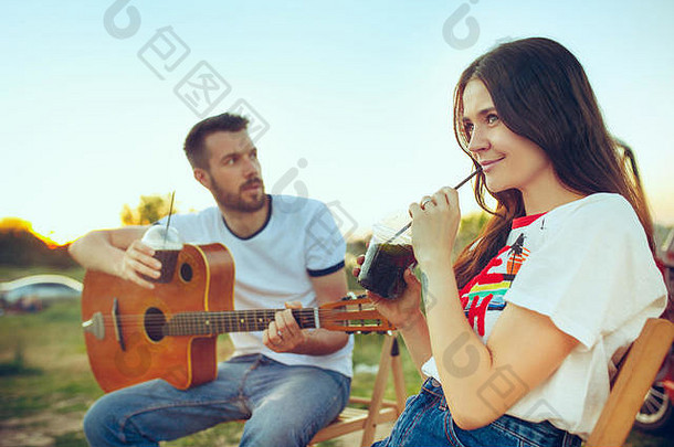 夫妇坐着休息海滩玩吉他夏天一天河