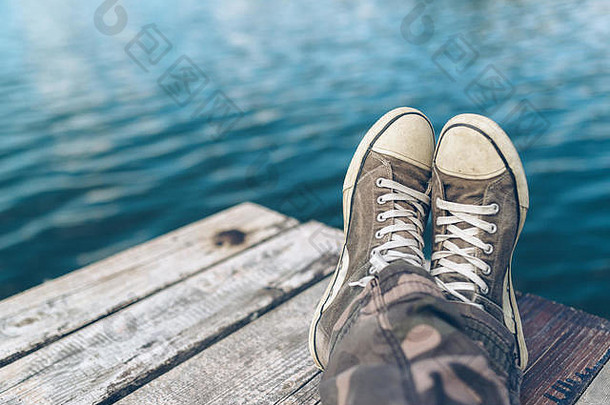 男人。交叉腿放松河岸码头休闲年轻的的家伙穿运动鞋坐着河夏天下午