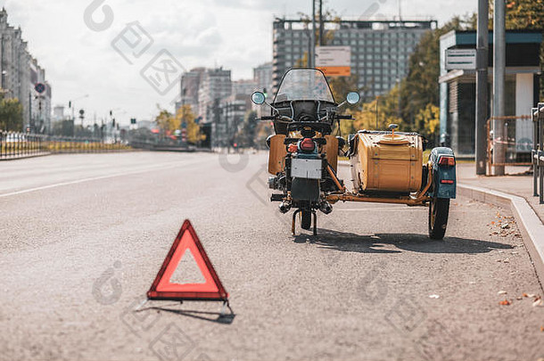 复古的摩托车双轮马车轮站边缘巷道警告三角形阳光明媚的秋天一天城市