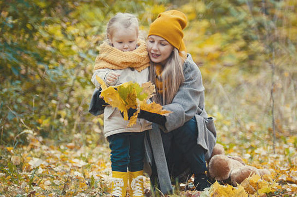 金发女郎女儿妈妈走秋天公园有趣的收集叶子关闭