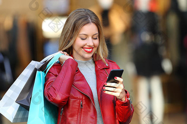 肖像快乐购物者持有购物袋聪明的电话商业中心