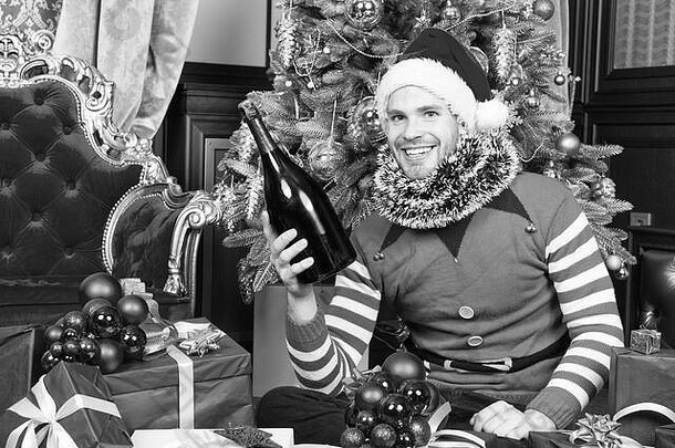 庆祝活动聚会，派对概念男人。圣诞老人他微笑香槟瓶快乐一年圣诞节假期男子气概精灵服装现在盒子圣诞节树礼物给拳击一天