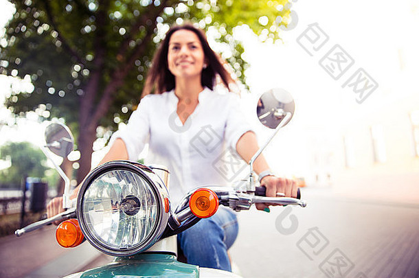 微笑年轻的女人踏板车在户外焦点踏板车