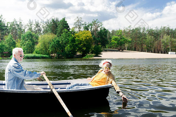 高级男人。划船船好奇的妻子触碰水