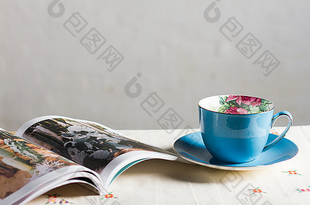 杂志花表格蓝色的茶杯飞碟前面平原白色墙