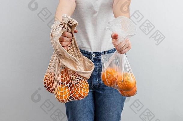 橙子水果塑料袋橙子纺织网袋女手白色墙背景浪费食物浪费概念