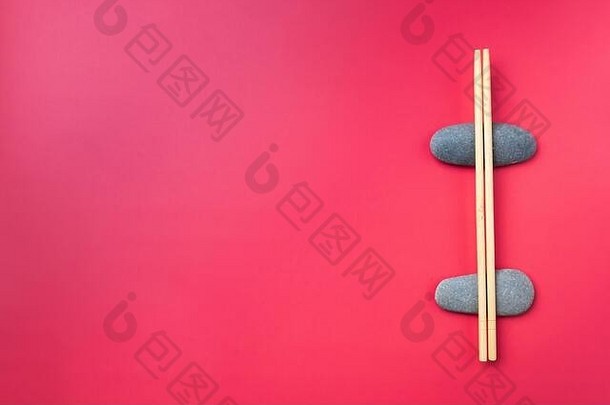 平躺光木筷子谎言椭圆形石头粉红色的背景传统的亚洲餐具复制空间