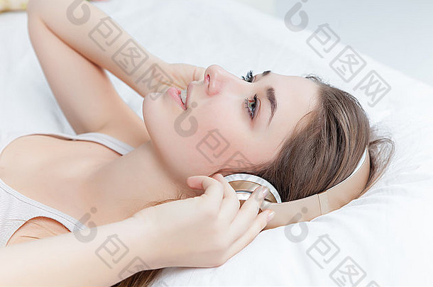 年轻的女孩床上听音乐耳机