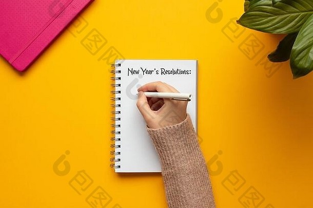 股票照片年轻的女人手写作一年笔记本列表决议对象黄色的背景
