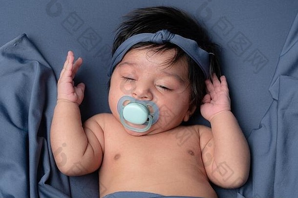 一半睡觉新生儿婴儿婴儿黑暗头发头巾铺设蓝色的背景奶嘴口