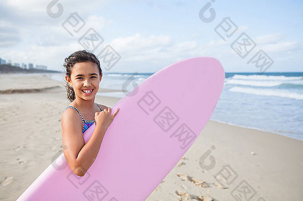 可爱的微笑年轻的女孩持有粉红色的冲浪板海滩