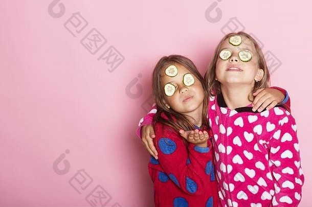 女孩明亮的粉红色的睡衣拥抱孩子们构成粉红色的背景发送吻复制空间孩子们微笑脸黄瓜眼睛宽松的头发童年友谊幸福概念