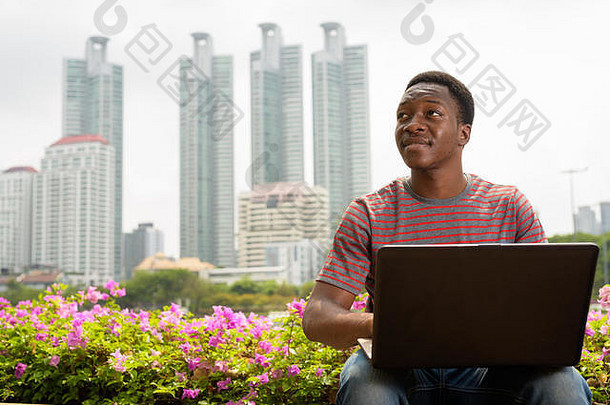 年轻的英俊的非洲男人。移动PC电脑公园
