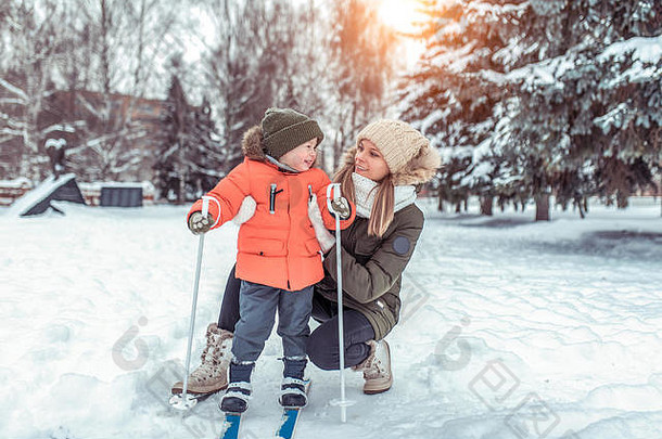 年轻的女人妈妈。支持护理男孩儿子年滑雪冬天森林公园体育教训街快乐