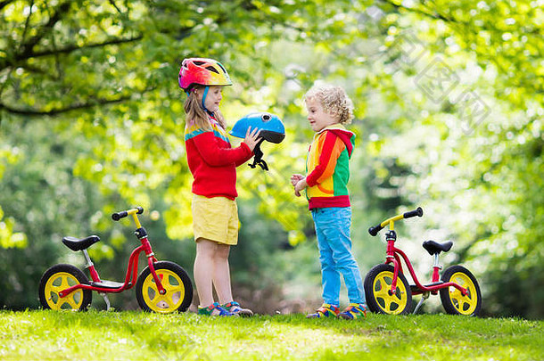 孩子们骑平衡自行车孩子们自行车阳光明媚的公园女孩男孩骑滑翔机自行车温暖的夏天一天学龄前儿童学习平衡