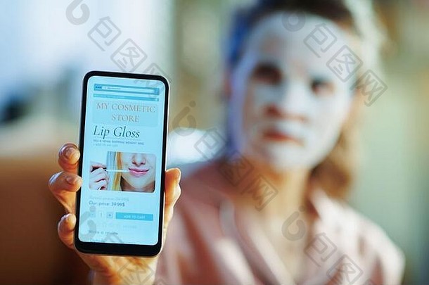 特写镜头优雅的中间年龄女人睡衣白色表面部面具脸显示智能手机美化妆在线购物网站模式