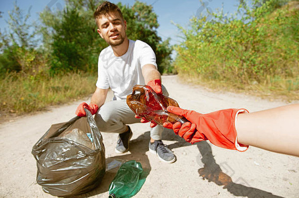 构建健康的首页集团志愿者整理垃圾海滩阳光明媚的一天年轻的男人。护理自然环境采取瓶包概念生态