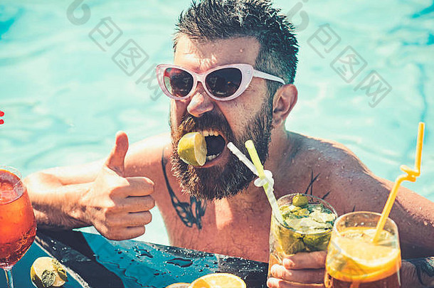 夏天假期迈阿密海滩马尔代夫男人。游泳喝酒精鸡尾酒水果有胡子的男人。池池聚会，派对维生素