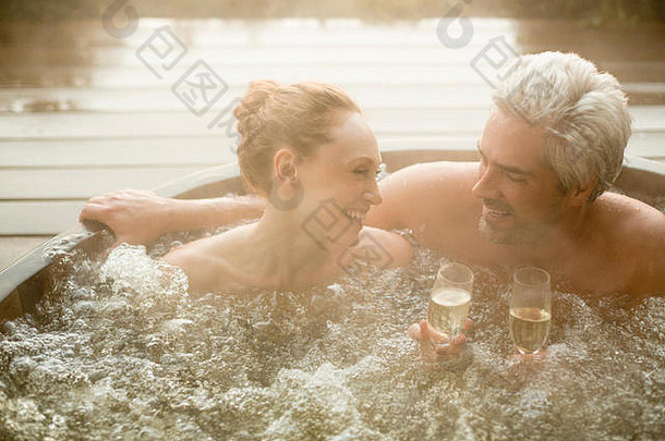 微笑夫妇喝香槟浸泡热浴缸天井