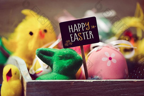 黄色的玩具小鸡绿色玩具兔子装饰鸡蛋黑色的招牌文本快乐复活节