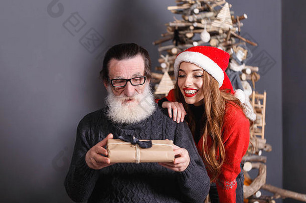 汉森高级爸爸白色胡子穿眼镜灰色的毛衣礼物年轻的长头发的女儿红色的毛衣穿圣诞老人他手表爸爸反应一年圣诞节假期记忆礼物购物折扣商店雪少女圣诞老人老人化妆发型狂欢节
