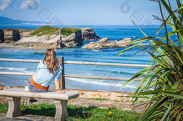 年轻的女人坐着板凳上面对海