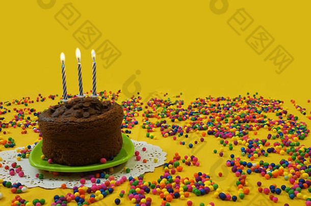 巧克力生日蛋糕蓝色的白色蜡烛基斯小绿色板包围糖果球分散黄色的背景