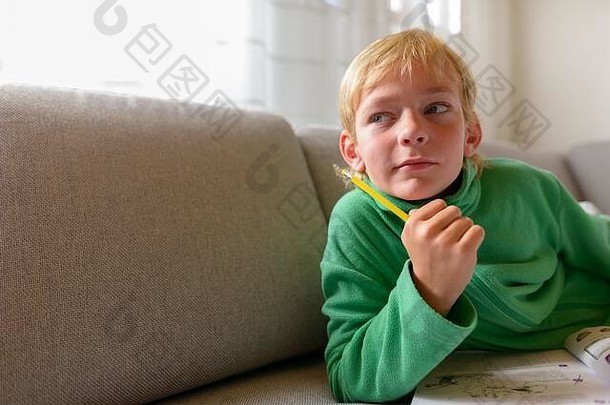 年轻的英俊的男孩思考研究沙发上首页