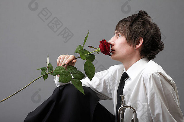 肖像年轻的男人。灰色背景爱玫瑰