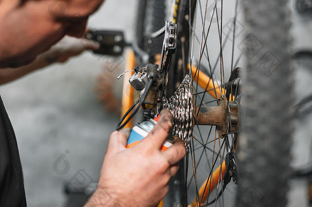 机械师男人。手喷涂石油自行车链自行车维护
