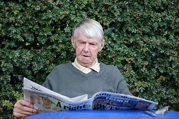 养老金男人。坐着在户外阅读报纸
