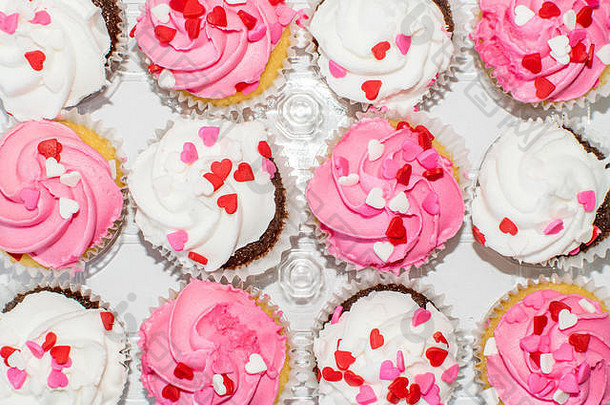 前视图安排粉红色的白色彩色的结霜奶油纸杯蛋糕装饰心洒