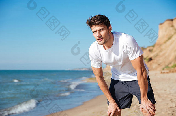 肖像英俊的年轻的男人。白色t恤短裤站海滩