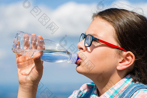 年轻的女孩喝水在户外