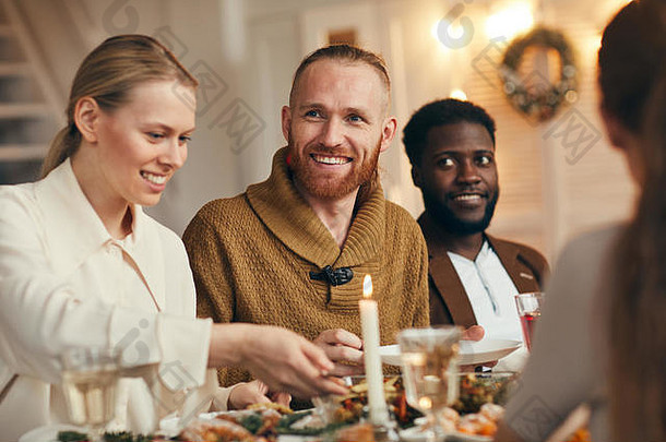 肖像当代有胡子的男人。微笑幸福的庆祝圣诞节朋友家庭晚餐表格